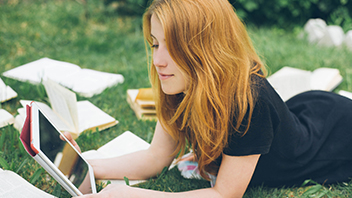 student-plays-on-tablet-in-the-grass
