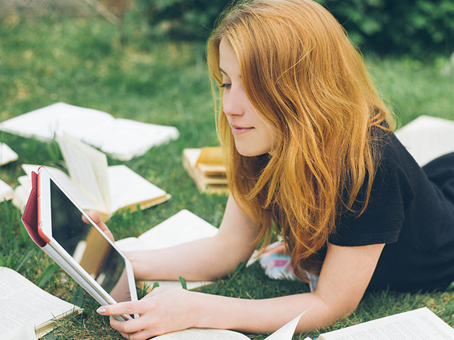 student-plays-on-tablet-in-the-grass